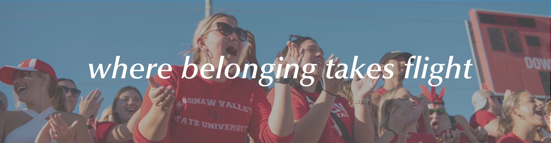 Students cheering in the student section of an SVSU football game with text overlaying the image that says 